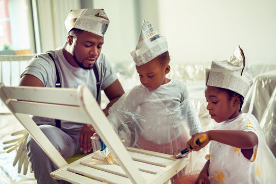 Father and children painting furniture with newspaper hats