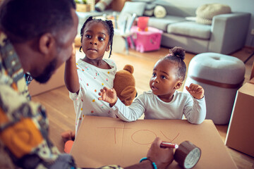 Father and daughters preparing a cardboard box for their toys at home