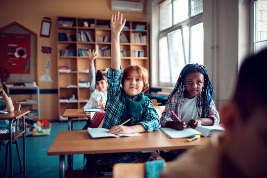 Eager student raising his hand in a diverse classroom