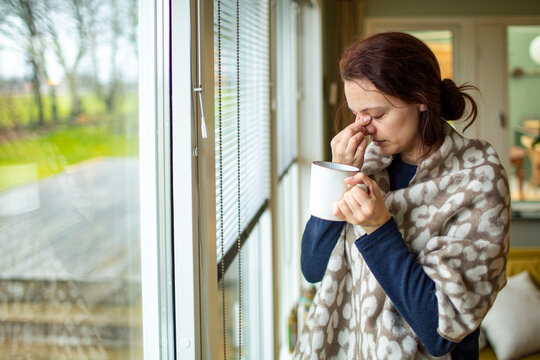 Woman Holding a Mug While Gazing Out of a Window - Powered by Adobe