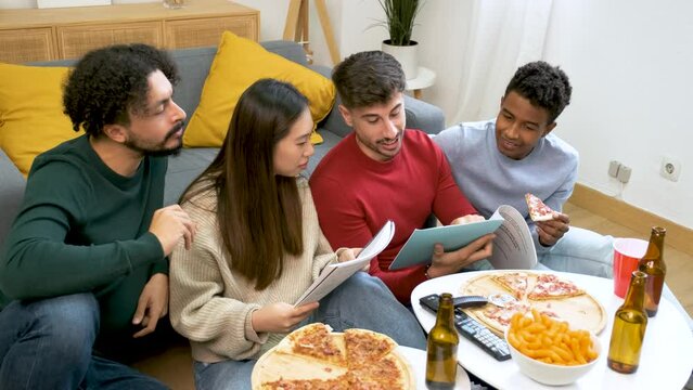 Group of diverse university colleagues studying and eating pizza together at shared students house.