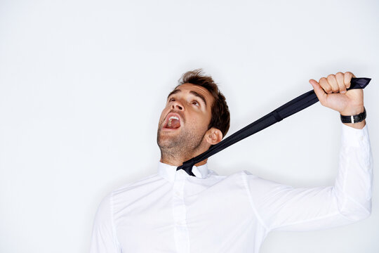 Stress, choke and tie with a business man in studio on a white background to fear or strangle. Depression, anxiety or mental health and a shouting young model choking his neck with a tight grip