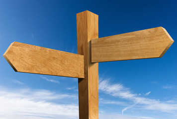Fototapeta premium Two empty wooden directional signs (arrows) with pole and copy space, against a clear blue sky with clouds.