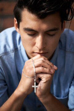 Man, hands and praying with crucifix for faith, worship and spirituality for soul, support and belief. Male person, confession and hope for forgiveness from god, gratitude and trust in religion