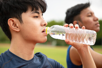 Two Asia male Athlete Drinking from a Water Bottle on the Track together; Mineral Water Stay Active...