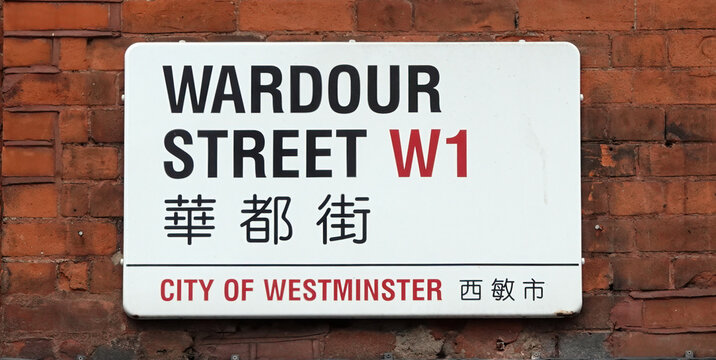 Closeup of Wardour Street sign in both English and Chinese on a brick wall in Westminster, London W1, UK. 