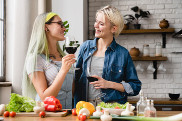 Two female couple girlfriends lesbians lgbtq women drinking wine looking at each other while...
