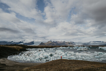 Woman in red jumper standing overlooking Jökulsárlón glacier lagoon in Iceland