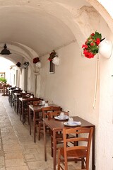 restaurant between buildings, tables placed in the passage between buildings, restaurant in a narrow street, Italian town