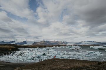 Woman in red jumper walking near J&ouml;kuls&aacute;rl&oacute;n glacier lagoon in Iceland