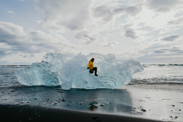 Man sitting inside the piece of ice in Diamond beach in Iceland