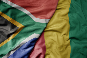 big waving national colorful flag of south africa and national flag of guinea .