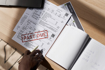 Top view closeup of unrecognizable man doing taxes at home with past due bill on table, copy space