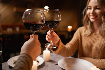 Valentine's Day concept. Happy young couple in love clinking glasses drinking wine, romantic dinner, celebrating Valentines Day sitting at table at home.