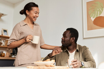 Side view portrait of young Black couple enjoying conversation in morning in cozy home