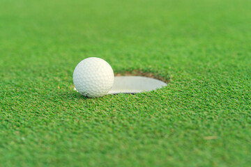 Golf ball on lip of cup at golf court