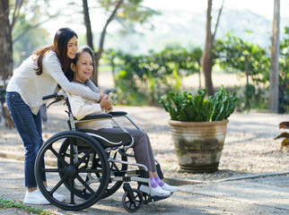 Asian senior woman in wheelchair with happy daughter. Family rel