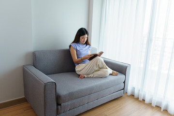 Fototapeta premium Asian Women reading book and relaxing at home and comfort in front of opened book