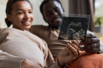 Close up of happy young Black couple expecting baby and holding ultrasound picture, copy space - obrazy, fototapety, plakaty
