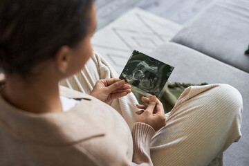 Portrait of pregnant young woman holding ultrasound picture of baby and enjoying motherhood, copy space - obrazy, fototapety, plakaty