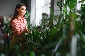 Woman florist working at her flower shop standing surrounded by plants