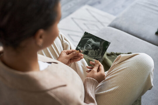 Portrait of pregnant young woman holding ultrasound picture of baby and enjoying motherhood, copy space