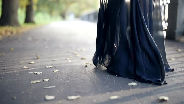 mysterious woman in black chiffon dress and red high heels shoes walking alone on city embankment