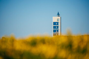 A modern lighthouse stands out in a blurry foreground