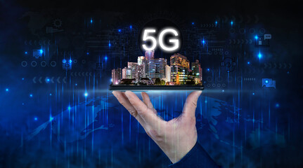 Creative background, male hand holding a phone with 5G hologram on city background. Concept of 5G network.