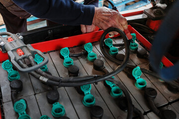 Forklift truck electric batteries being topped up at the regular maintenance check mans hand closeup with water hose - obrazy, fototapety, plakaty