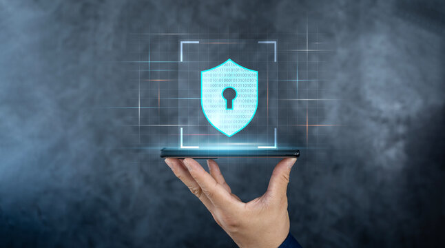 Cyber security technology and data protection privacy concepts. Shield icon on futuristic transparent smart mobile phone in hand surrounded with binary code. - Powered by Adobe