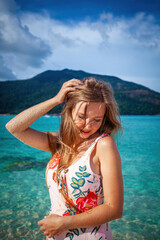 Obraz premium Beautiful caucasian woman relaxing by the sea on a sunny beach. Concept of summer vacation and enjoying the outdoors.