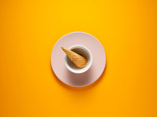Ice cream cone in a white bowl over yellow background.