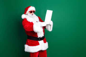 Photo of impressed funny santa dressed red costume reading new year disobedient kids list empty space isolated green color background