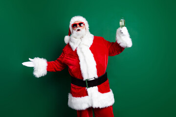Fototapeta na wymiar Photo of excited good mood santa dressed red costume telling new year toasts rising wine glass isolated green color background