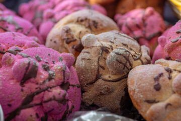 Traditional Day of the Dead puff pastry or Day of the Dead bread with chocolate and strawberry on tray for sale in a market in Mexico