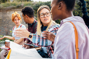 Diverse group of students sitting outdoor takling and learning together.