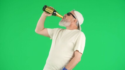 Portrait of senior man hipster on Chroma key green screen background, man in white t-shirt drinking champagne from bottle. Advertising area, workspace mockup.