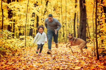 Naklejka na ściany i meble Father and daughter having fun running in autumn park