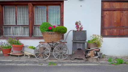 Fototapeta na wymiar Quaint tradtional European residential decoration in Swiss street. Flower pots and rural accessories on display in cottage Switzerland
