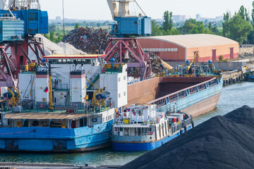 Side view of blue large general cargo ship (bulk carrier) with open deck standing moored in city...