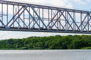 Obraz premium Side view of empty old metal railway bridge standing on Don river in a summer cloudy day. Soft focus. General architecture theme.