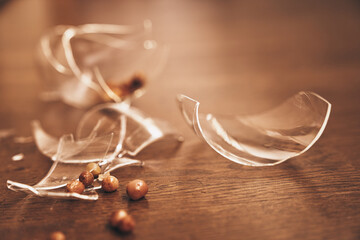 Close-up of a broken transparent glass of compote with raisins. Pieces of broken glass lie on the...