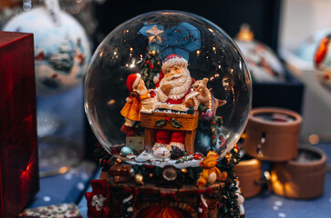 Festive magic details. Magic crystal ball with a toy Santa Claus and Elf. New Year souvenir and Christmas cute gift.