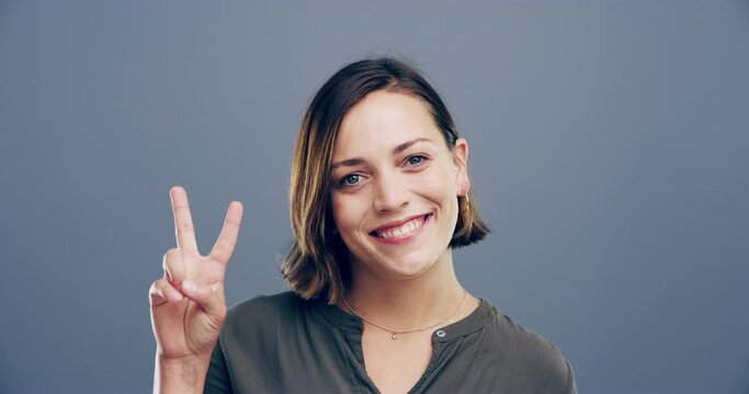 Face, smile and woman with peace sign in studio isolated on a gray background mockup space. Portrait, happy person and v hand gesture for victory, winner symbol and emoji for achievement of success