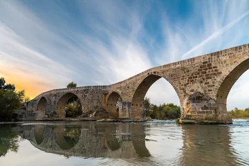Fototapeten The historical Aspendos Bridge over Koprucay at sunrise in Antalya Turkey © yalcinsonat