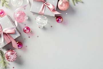 Elegant Christmas background with gift boxes and pink baubles, decorations on gray table. Top view.