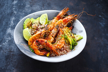 Traditional Thai fried king prawns with Asian vegetable, avocado slices and rice served as close-up on a design plate with text space