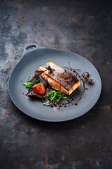 Traditional Japanese gourmet salmon fish steak tataki with algae, umeboshi fruit and wakame served as close-up on a design plate with copy space