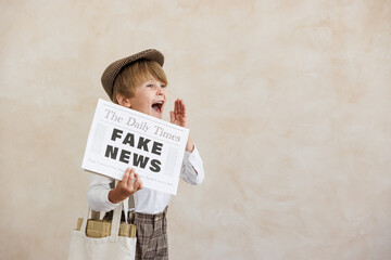 Newsboy shouting against grunge wall background. Boy selling fake news - obrazy, fototapety, plakaty